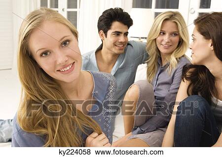 Stock Photo - Four friends gossiping in a living room. Fotosearch