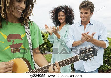 Man playing a guitar and his friends applauding him View Large Photo Image Stock Photography - Man playing a guitar and his friends applauding him. Fotosearch