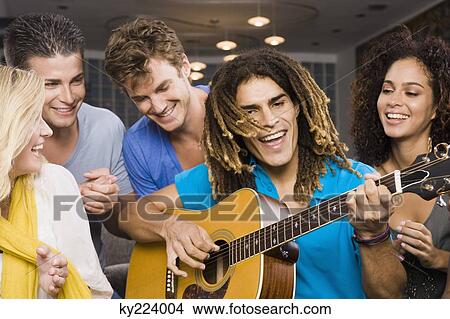 Man sitting with his friends and playing a guitar View Large Photo Image Picture - Man sitting with his friends and playing a guitar. Fotosearch
