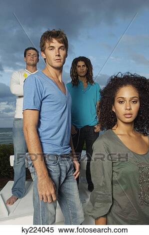 Stock Photography - Portrait of four friends standing on the beach. Fotosearch