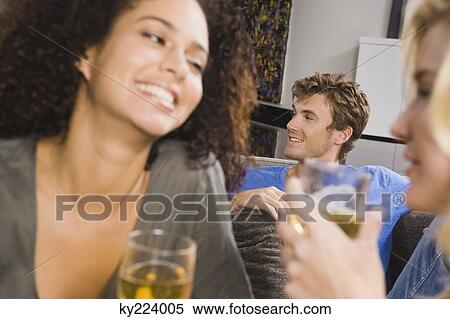 Stock Photography - Three friends enjoying drinks at a party. Fotosearch