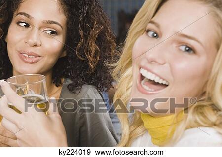 Two women enjoying drinks in a party View Large Photo Image Stock Photo - Two women enjoying drinks in a party. Fotosearch
