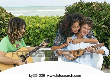 Stock Photograph - Woman embracing a man playing ukulele. Fotosearch