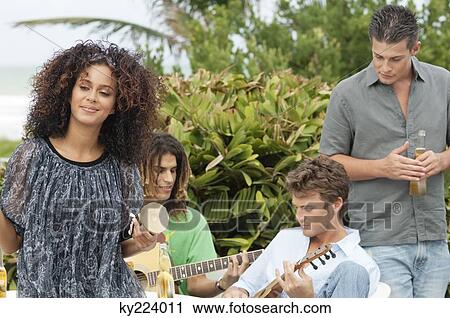 Woman holding a drum with her friends playing guitars View Large Photo Image Stock Image - Woman holding a drum with her friends playing guitars. Fotosearch