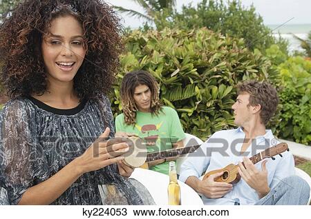 Stock Image - Woman with her friends playing musical instruments. Fotosearch