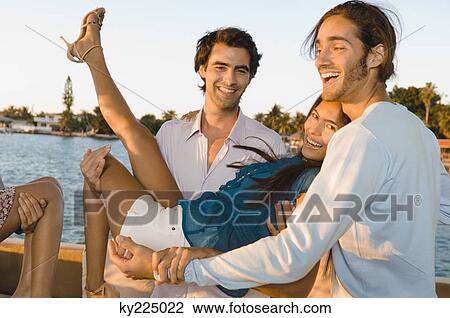 Man carrying a woman with his friend beside him View Large Photo Image Stock Image - Man carrying a woman with his friend beside him. Fotosearch