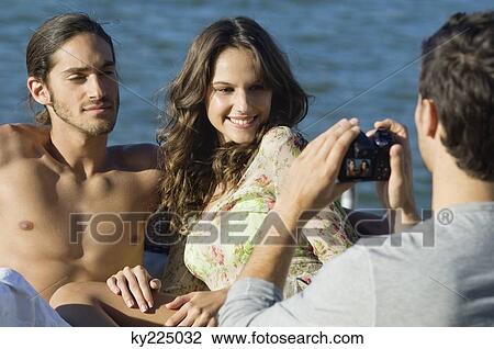 Stock Image - Man taking a picture of his friends with a digital camera. Fotosearch