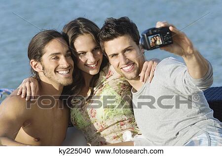 Three friends taking a picture of themselves with a digital camera View Large Photo Image Stock Image - Three friends taking a picture of themselves with a digital camera. Fotosearch