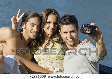 Three friends taking a picture of themselves with a digital camera View Large Photo Image Stock Photo - Three friends taking a picture of themselves with a digital camera. Fotosearch