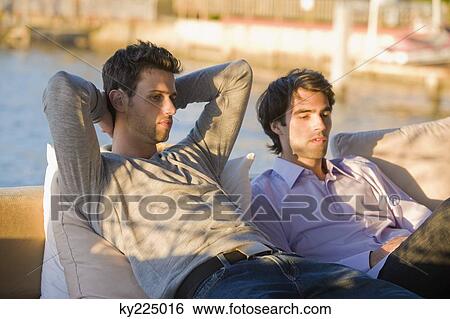 Stock Photograph - Two friends sitting in a tourist resort. Fotosearch