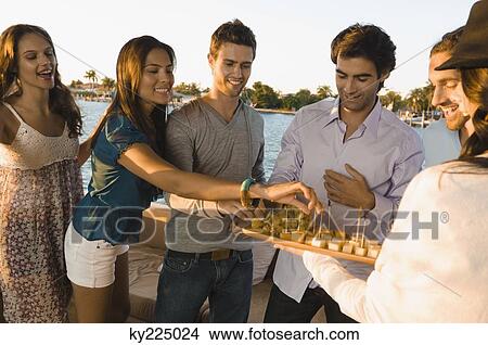 Picture - Woman serving fruits to her friends. Fotosearch