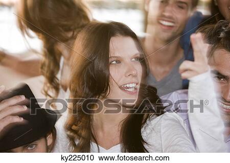 Stock Image - Woman smiling with her friends beside her. Fotosearch