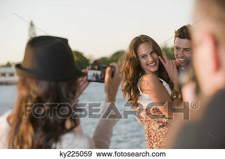 Woman taking a picture of her friends with a camera View Large Photo Image Stock Photo - Woman taking a picture of her friends with a camera. Fotosearch