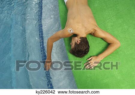High angle view of a man sunbathing at the poolside View Large Photo Image Stock Image - High angle view of a man sunbathing at the poolside. Fotosearch