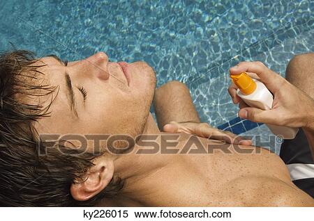 Man applying suntan lotion on his body at the poolside View Large Photo Image Stock Photography - Man applying suntan lotion on his body at the poolside. Fotosearch