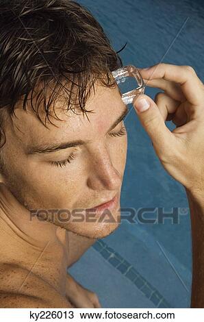 Man rubbing an ice cube on his forehead View Large Photo Image Stock Image - Man rubbing an ice cube on his forehead. Fotosearch