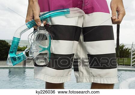 Mid section view of a man holding a scuba mask at the poolside View Large Photo Image Stock Photograph - Mid section view of a man holding a scuba mask at the poolside. Fotosearch