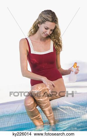 Woman applying suntan lotion at the poolside View Large Photo Image Picture - Woman applying suntan lotion at the poolside. Fotosearch