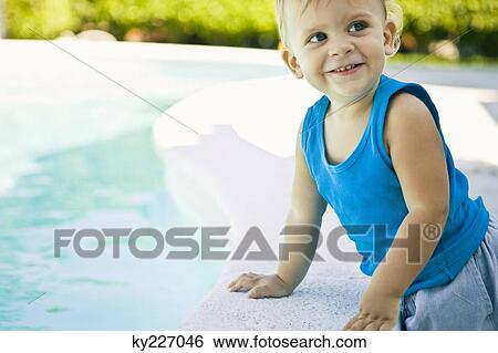 Baby boy leaning on the ledge at the poolside View Large Photo Image Stock Photograph - Baby boy leaning on the ledge at the poolside. Fotosearch