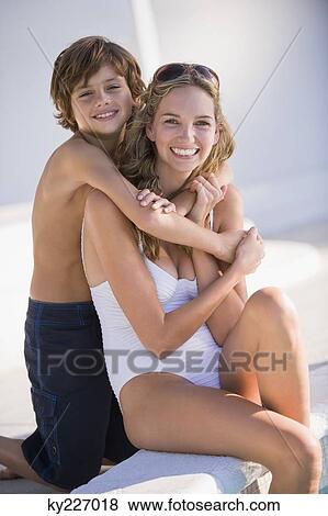 Stock Photo - Boy hugging his mother at the poolside and smiling. Fotosearch
