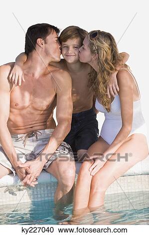 Stock Image - Couple kissing their son at the poolside. Fotosearch