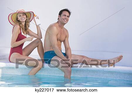 Stock Photo - Couple sitting at the poolside. Fotosearch