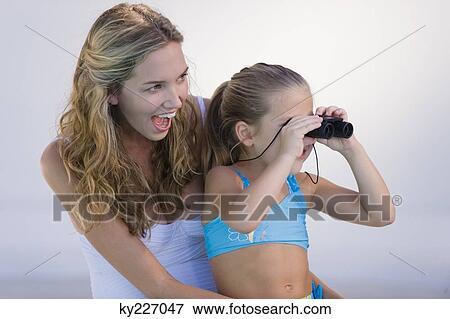 Girl looking through binoculars with her mother laughing View Large Photo Image Stock Photo - Girl looking through binoculars with her mother laughing. Fotosearch