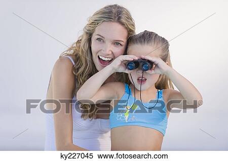 Stock Photography - Girl looking through binoculars with her mother laughing. Fotosearch