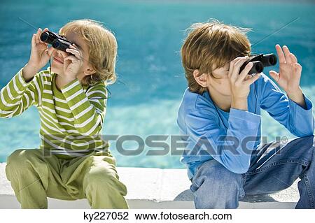 Two boys looking through binoculars at the poolside View Large Photo Image Stock Image - Two boys looking through binoculars at the poolside. Fotosearch