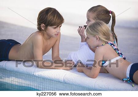 Stock Photograph - Two girls and a boy at the poolside. Fotosearch