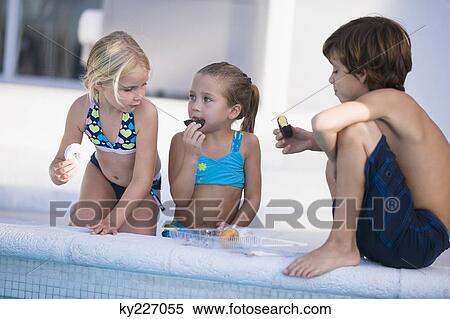 Two girls and a boy eating chocolate donuts at the poolside View Large Photo Image Stock Photography - Two girls and a boy eating chocolate donuts at the poolside. Fotosearch