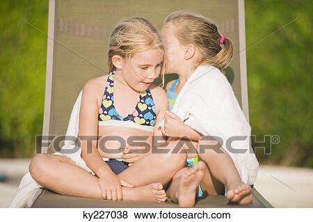 Two girls sitting on a lounge chair and whispering View Large Photo Image Stock Photo - Two girls sitting on a lounge chair and whispering. Fotosearch