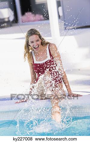 Woman sitting at the poolside and splashing water View Large Photo Image Stock Photo - Woman sitting at the poolside and splashing water. Fotosearch