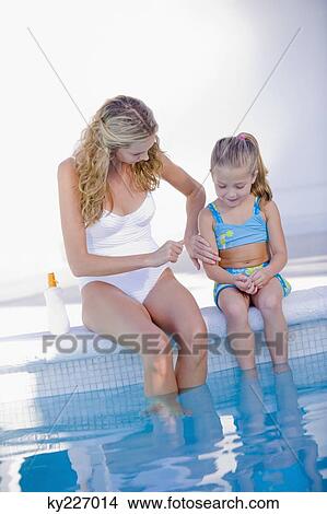 Woman with her daughter sitting at the poolside View Large Photo Image Picture - Woman with her daughter sitting at the poolside. Fotosearch