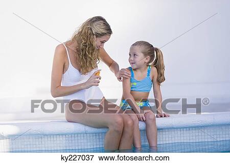 Woman with her daughter sitting at the poolside View Large Photo Image Stock Photo - Woman with her daughter sitting at the poolside. Fotosearch