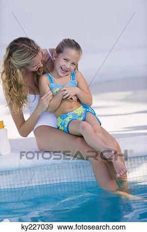 Woman with her daughter sitting at the poolside View Large Photo Image Stock Photo - Woman with her daughter sitting at the poolside. Fotosearch