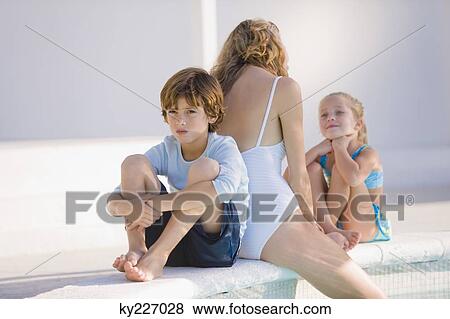 Stock Photo - Woman with her two children sitting at the poolside. Fotosearch