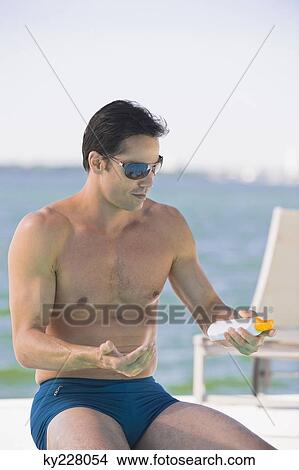 Man applying suntan lotion at the poolside View Large Photo Image Picture - Man applying suntan lotion at the poolside. Fotosearch