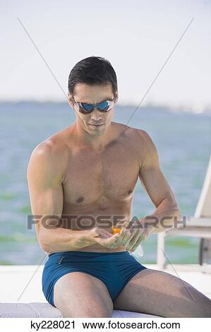 Man applying suntan lotion at the poolside View Large Photo Image Stock Image - Man applying suntan lotion at the poolside. Fotosearch