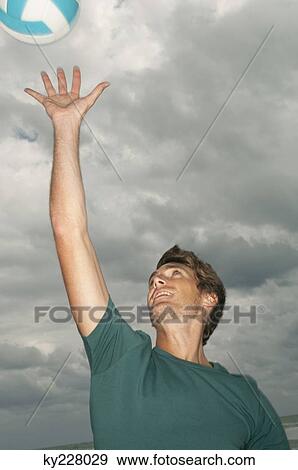 Stock Photo - Man playing volleyball on the beach. Fotosearch