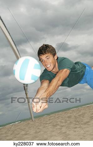 Stock Photo - Man playing volleyball on the beach. Fotosearch