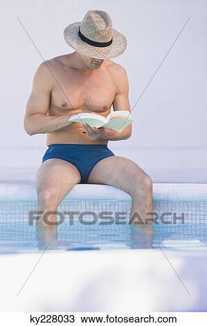 Man reading a book at the poolside View Large Photo Image Stock Image - Man reading a book at the poolside. Fotosearch