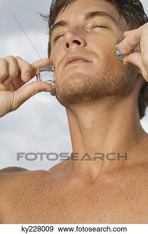 Man rubbing ice cubes on his cheeks View Large Photo Image Stock Photo - Man rubbing ice cubes on his cheeks. Fotosearch