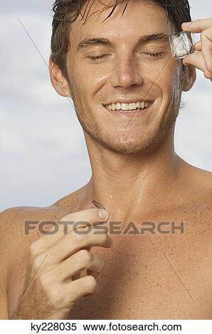 Man rubbing ice cubes on his face View Large Photo Image Stock Photography - Man rubbing ice cubes on his face. Fotosearch