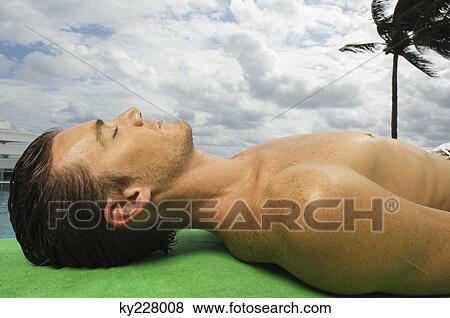 Man sunbathing at the poolside View Large Photo Image Stock Photo - Man sunbathing at the poolside. Fotosearch