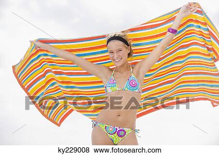 Portrait of a woman holding a beach towel and smiling View Large Photo Image Stock Photo - Portrait of a woman holding a beach towel and smiling. Fotosearch