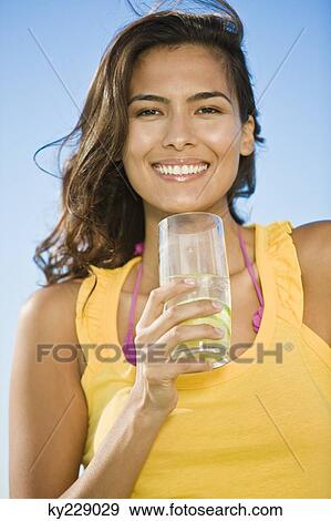 Woman holding a glass of lemonade View Large Photo Image Stock Photo - Woman holding a glass of lemonade. Fotosearch