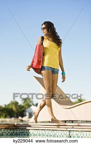 Woman walking with a bag at the poolside View Large Photo Image Picture - Woman walking with a bag at the poolside. Fotosearch