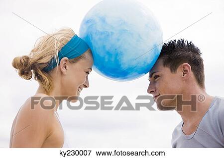 Couple balancing beach ball between their heads View Large Photo Image Stock Photo - Couple balancing beach ball between their heads. Fotosearch