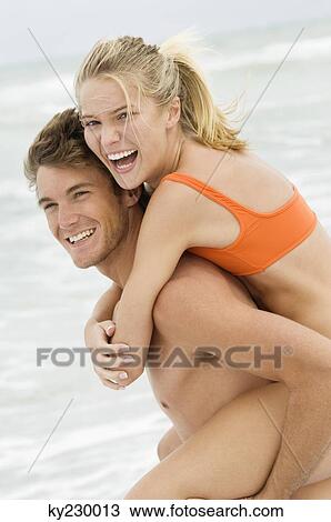 Man giving woman piggyback ride on the beach View Large Photo Image Stock Image - Man giving woman piggyback ride on the beach. Fotosearch